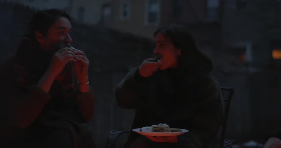People sitting by a fire and eating s'mores at night