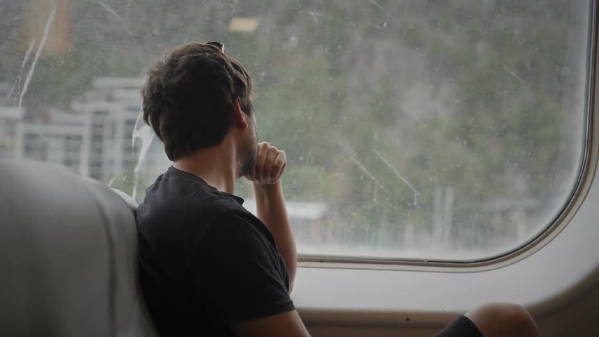 A man is sitting inside somewhere and looking out the window