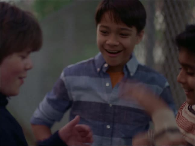 Three kids having a fun time playing near a fence with their fist