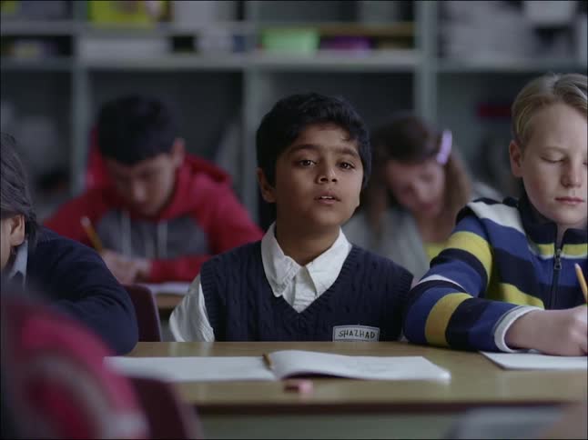 A student child sitting in the classroom next to their classmates and observing