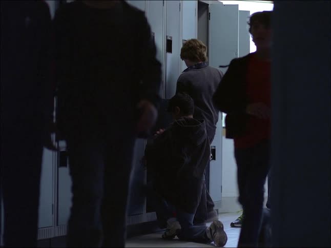 Several teenage boys putting away and retrieving clothes from school lockers