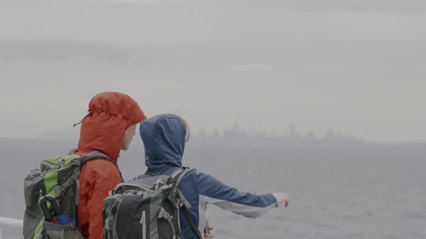Two people one facing forward and the other facing backward on a boat observing the sea