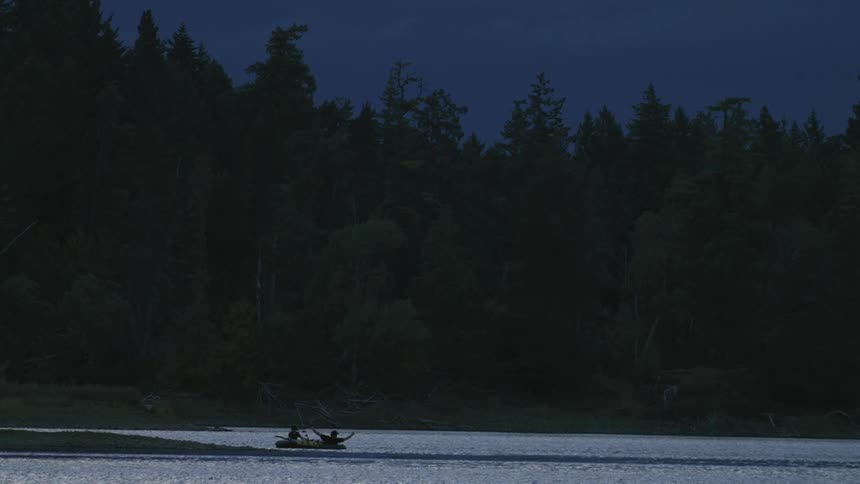 Two people in a canoe near the river bank