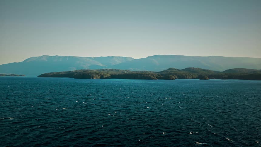 A huge ocean of blue water and on the horizon a land and mountains in the background