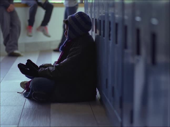 A teenager sitting beside the school cabinet