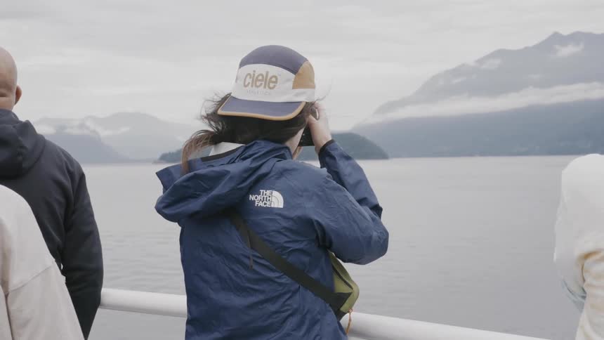 People on a ship photographing the landscape with mountains
