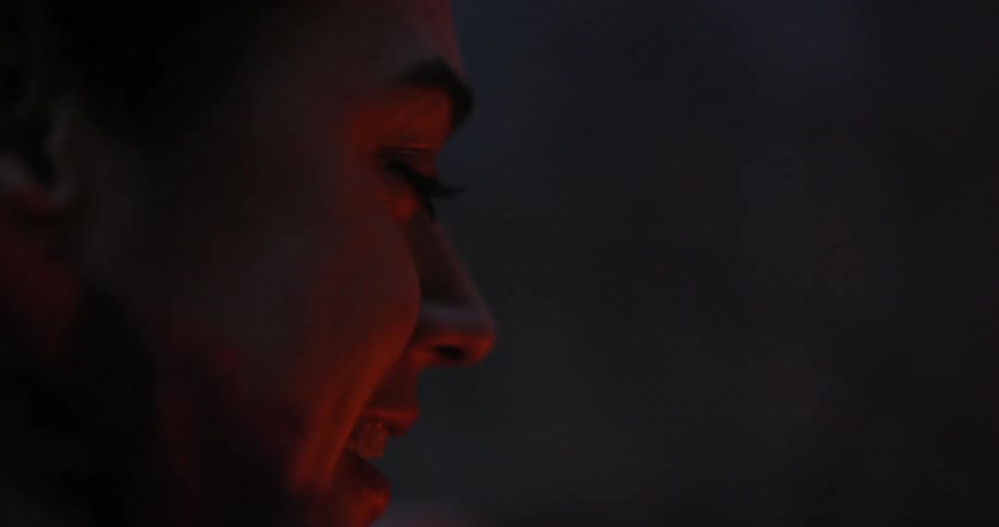A woman laughs and talks in the glow of a fire
