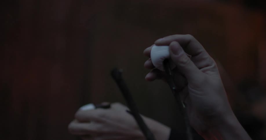 A person puts a marshmallow on a stick