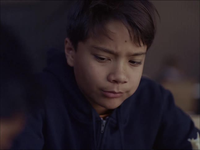 A boy eating while looking at someone