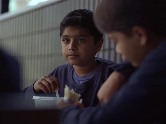 Three children sitting on the floor and eating