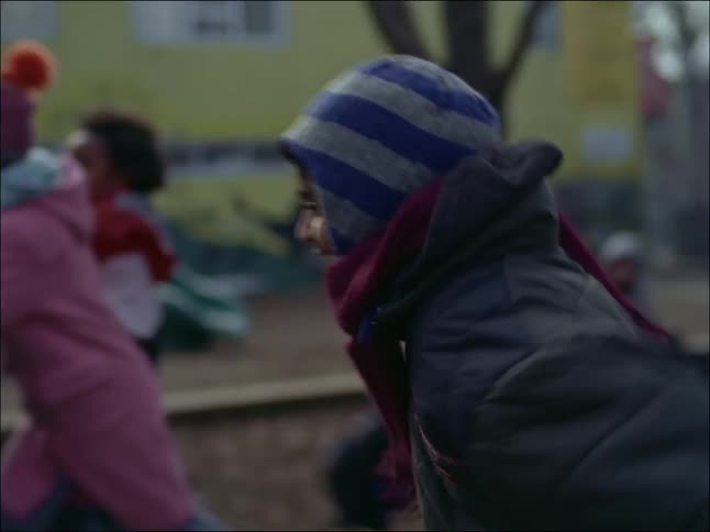 Several children in warm clothes are running and playing