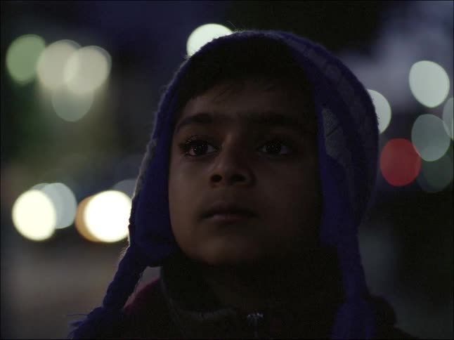 A little boy in a purple cap looks ahead and starts to walk