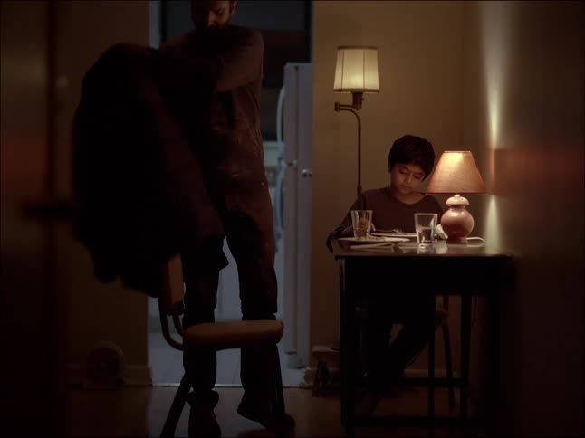 Father and son eating at the table and then the father gets up puts on his coat and pats his sons head