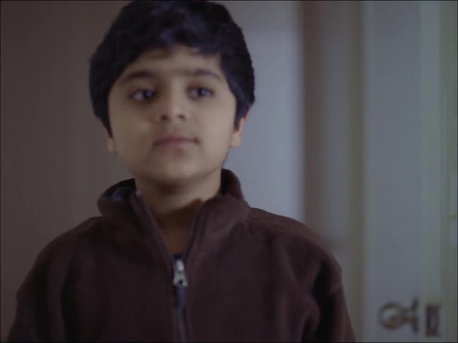 A child is taking off his winter jacket and placing it inside the wardrobe