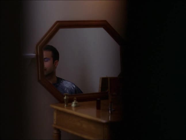 An adult male sited in front of a mirror starring at the door