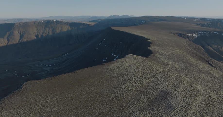 A plateau of mountains with a little snow under a morning sky