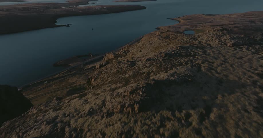 The top of a mountain and at the base there is a coast with the sea