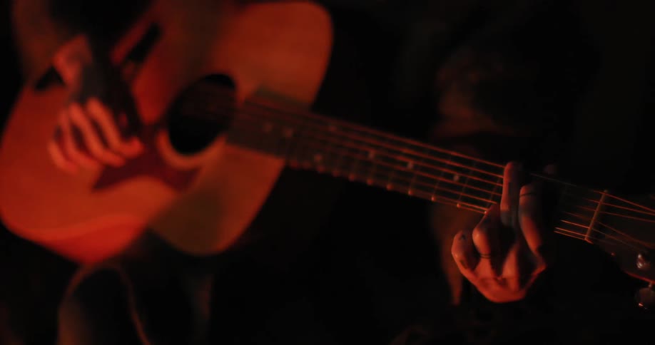 A person is playing the guitar in a dark area