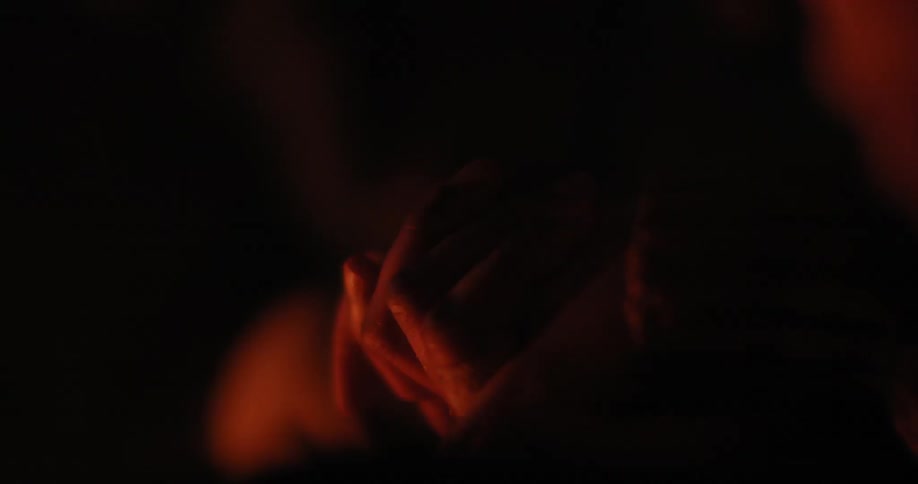 People hold hands by a fire at night