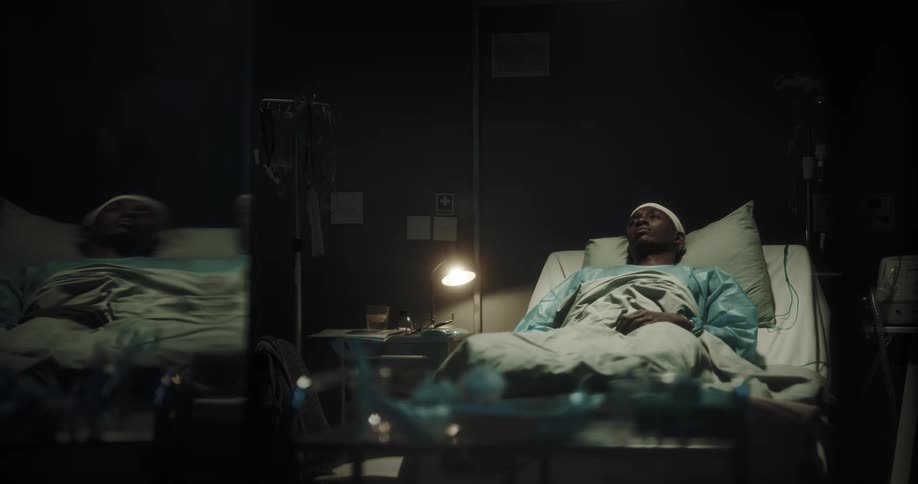 Man shaking his head and drowsy on a hospital stretcher at night