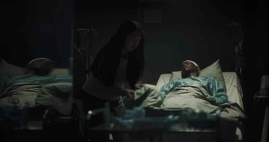 A woman spreads a blanket on a hospital patient