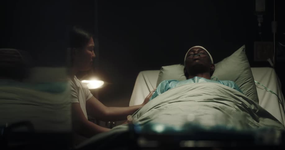 Man on a stretcher with a woman beside him touching him and crying