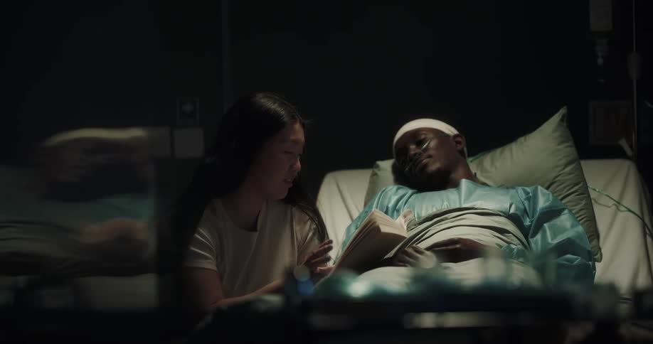 Woman reading a book to her partner who is lying on a hospital stretcher