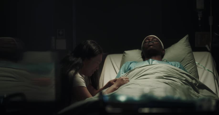A sick man in a hospital bed and a woman crying