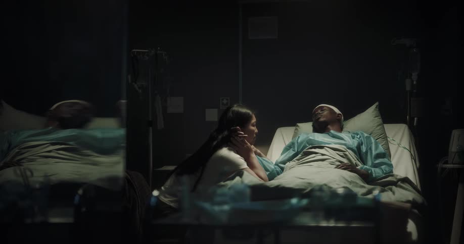 Woman crying beside her unconscious boyfriend lying on a hospital stretcher