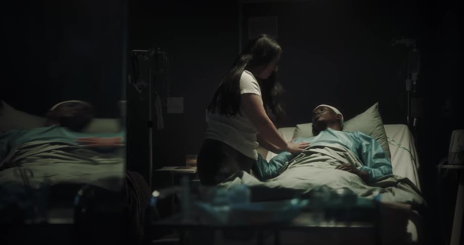 A woman saying goodbye to a man in a hospital bed