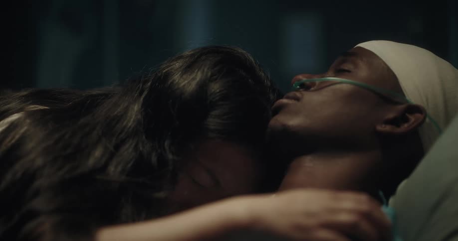 Lady weeps while caressing a sick black man on the hospital bed