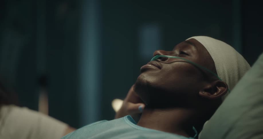 A woman talks with a hospital patient and touches his face