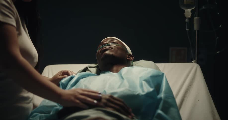 Man lying on a hospital stretcher with a woman beside him talking and smiling