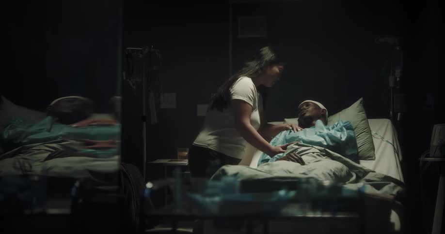 Woman leans over to kiss forehead of man lying in hospital bed