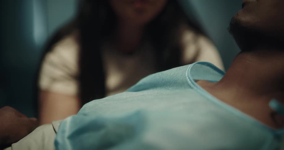 A woman crying on the bed of an unconscious man in the hospital