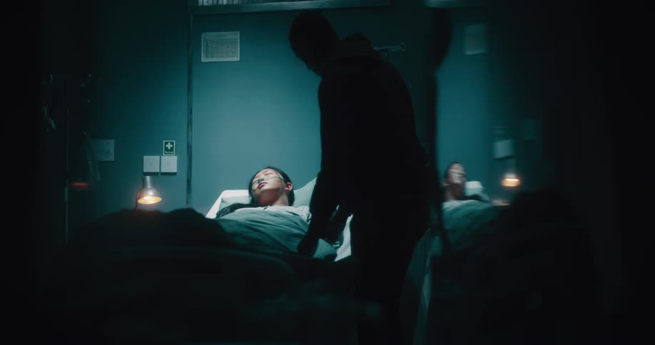 A black man caress the head an asian lady sleeping on hospital bed