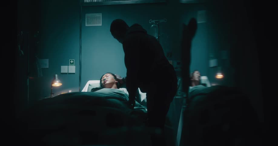 A man kissing his wife who is sleeping on a hospital stretcher