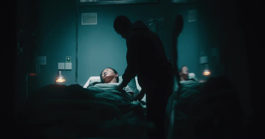 A man adjusts the blanket of a sleeping hospital patient