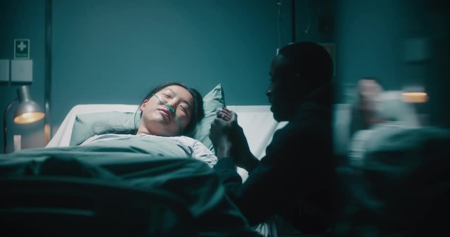 A man holding the hands of a woman who is lying on the hospital stretcher