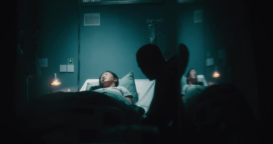 A man sits by the sleeping patient