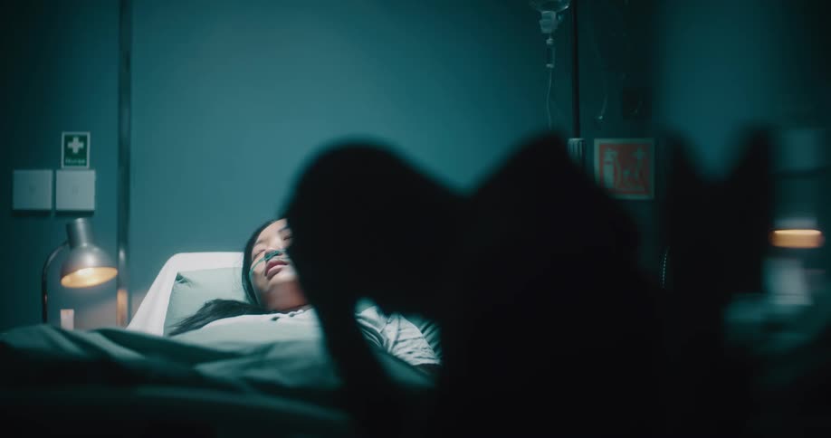 A man is worried as he visits a sleeping patient in the hospital