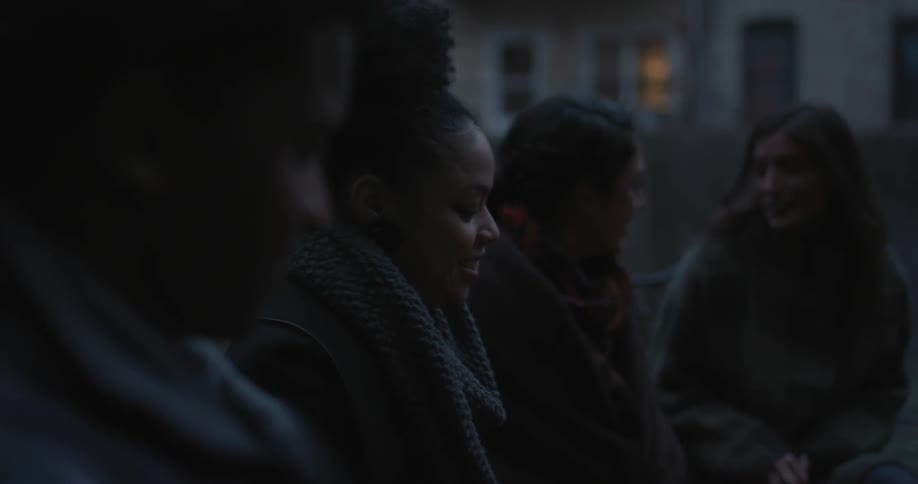A row of people talk outside at dawn