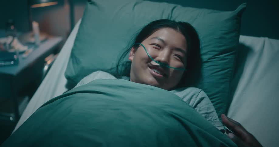 Woman lying on a hospital stretcher waking up to a hand from another person