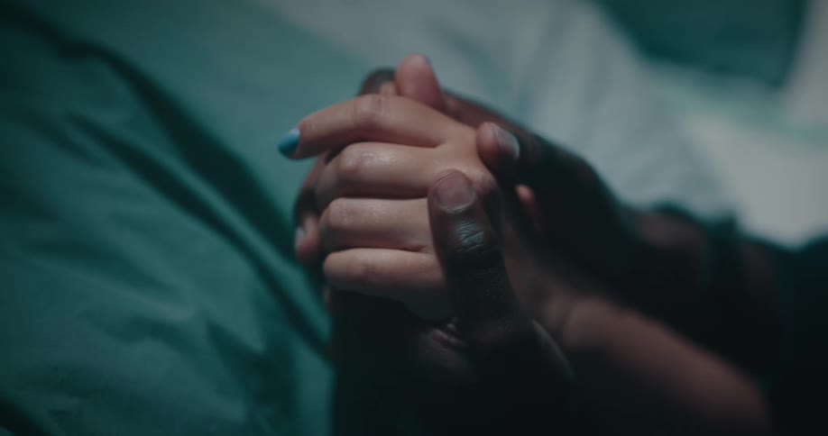 A black man holds a ladys hand rubbing his thumbs on it