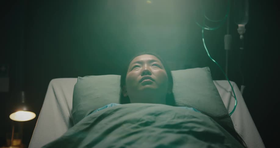 Asian lady lays on the hospital bed receiving drip at night