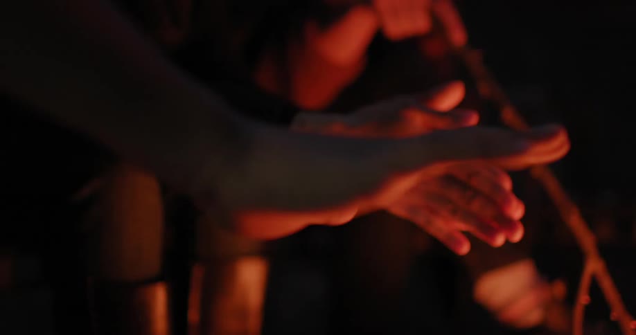 People are warming their hands on a campfire
