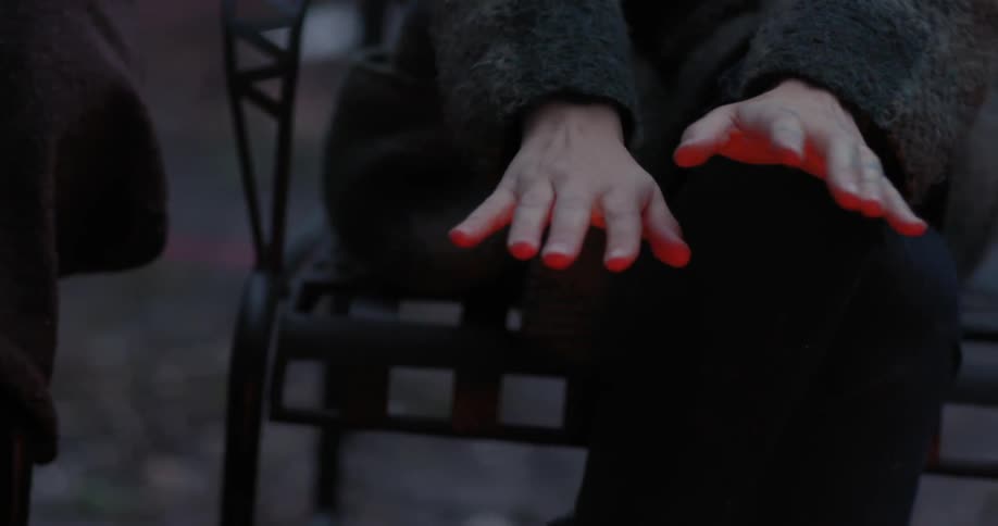A woman warming her hands over a campfire at night