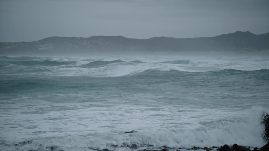 Waves crash against the rocks along the shore