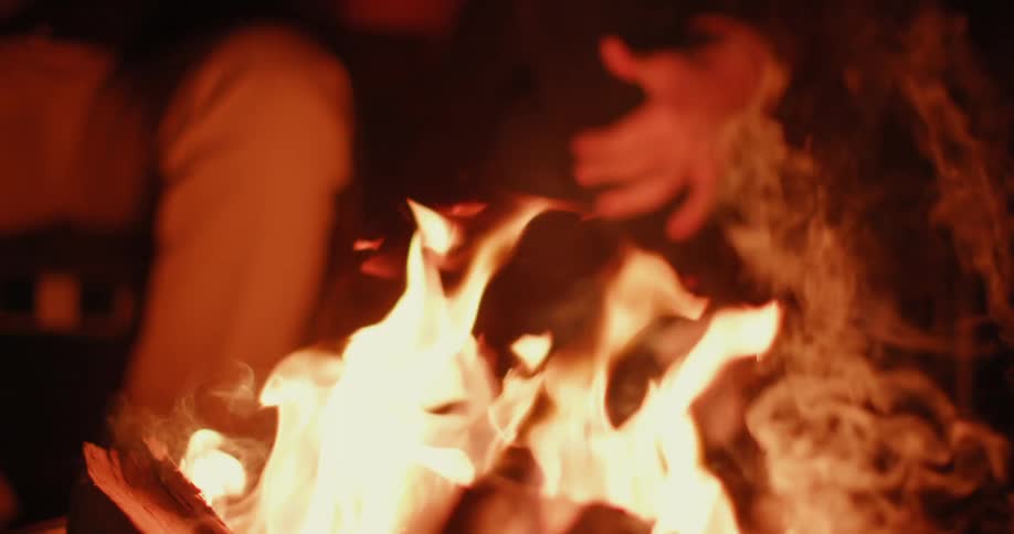 People sit around a campfire at night