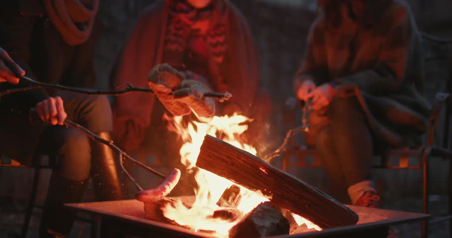 People cook over a camp fire at night